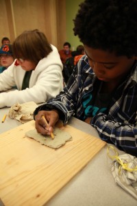 Children in the Mesopotamia edu-larp writing on clay